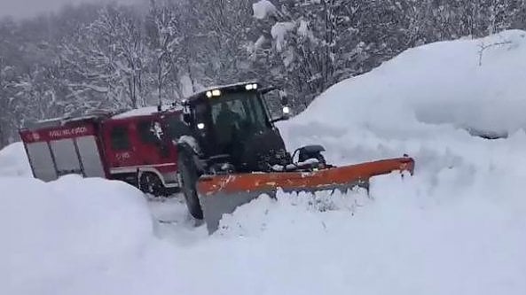 Il trattore lotta con la neve per trainare il camion dei Vigili del fuoco    