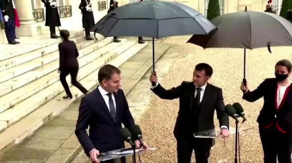 Evento sotto la pioggia all'Eliseo e Macron si improvvisa 'ombrellino'