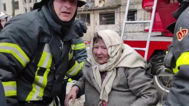 Anziani vengono soccorsi dai vigili del fuoco tra le fiamme dopo il bombardamento di un palazzo a Kiev